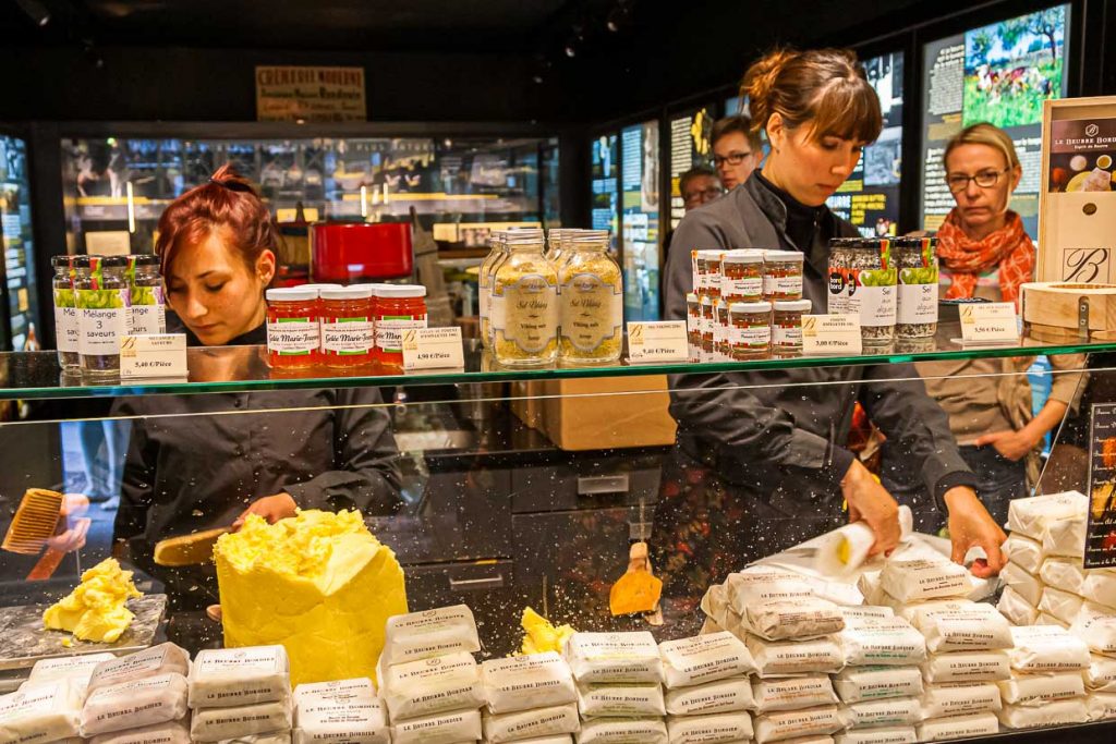 Im Maison du Beurre können Kunden dem Schlagen der Butter zuschauen.  Verkauft werden verschiedene auch aromatisierte Buttersorten / © Foto: Georg Berg