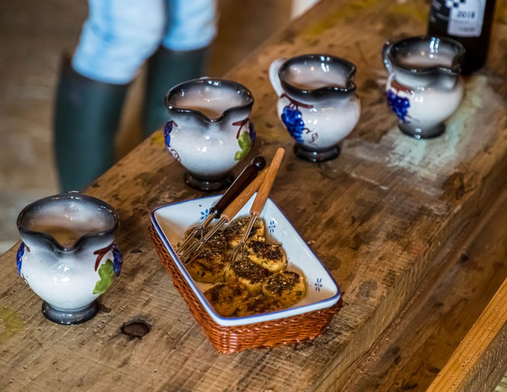 Zur Begrüßung gibt es kleine Fischfrikadellen und ein typisches Sommergetränk. Aus kleinen Keramikkrügen wird einfacher Weisswein gemischt mit Limonade serviert / © Foto: Georg Berg