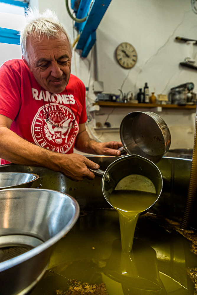 Nach dem Pressvorgang, steht das Wasser-Öl-Gemisch in offenen Behältern. Nach gut einer Stunde beginnt Fabrice Godet damit, das oben schwimmende Olivenöl abzuschöpfen. Das Fruchtwasser sinkt nach unten / © Foto: Georg Berg