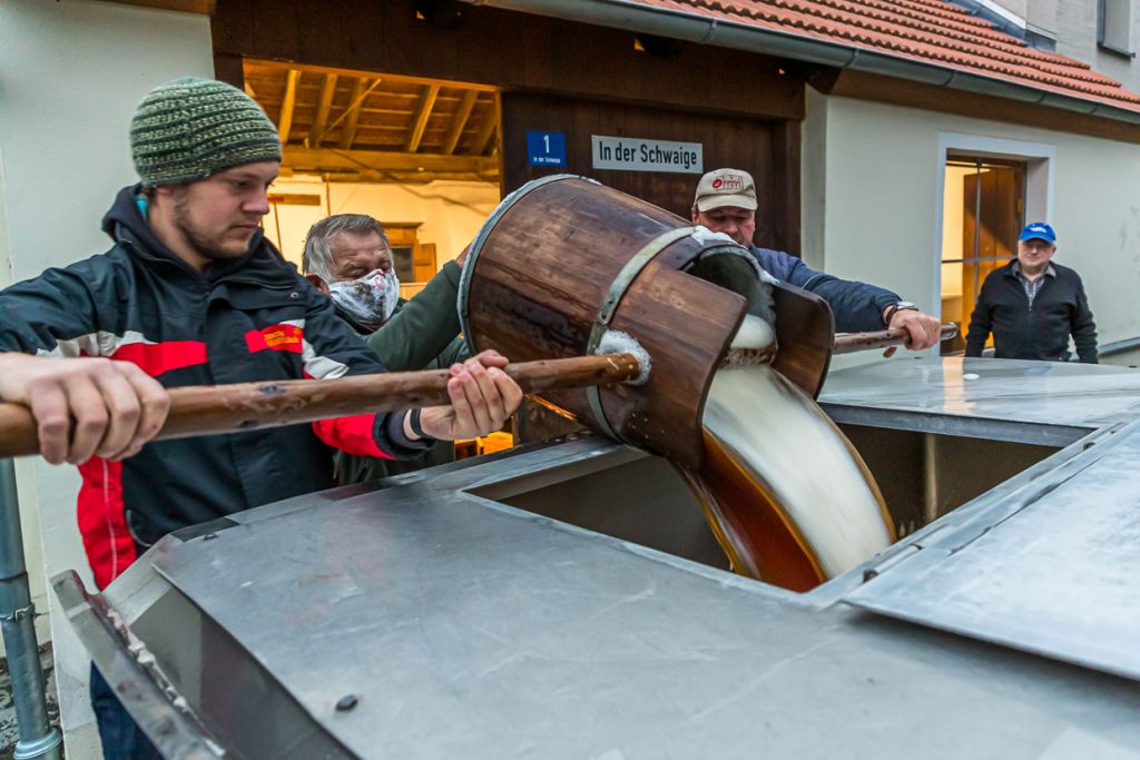 Schwungvoll wird die Zoigl-Stammwürze mit traditionellen Holzeimern in den Tankwagen gefüllt / © Foto: Georg Berg