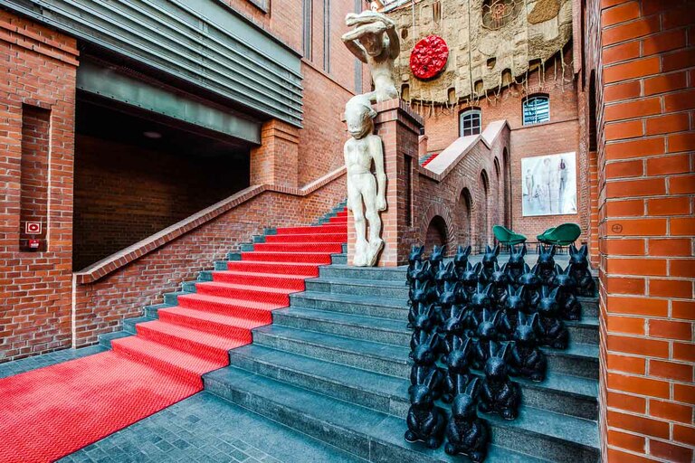 El impresionante vestíbulo del Hotel Blow up 5050, Poznan. Polonia. Como invitado, inmediatamente querrá seguir la alfombra roja. Pasa junto a obras de arte contemporáneo, como esculturas y fotografías. El huésped del hotel es conducido directamente al igualmente gigantesco bar del hotel / © Foto: Georg Berg