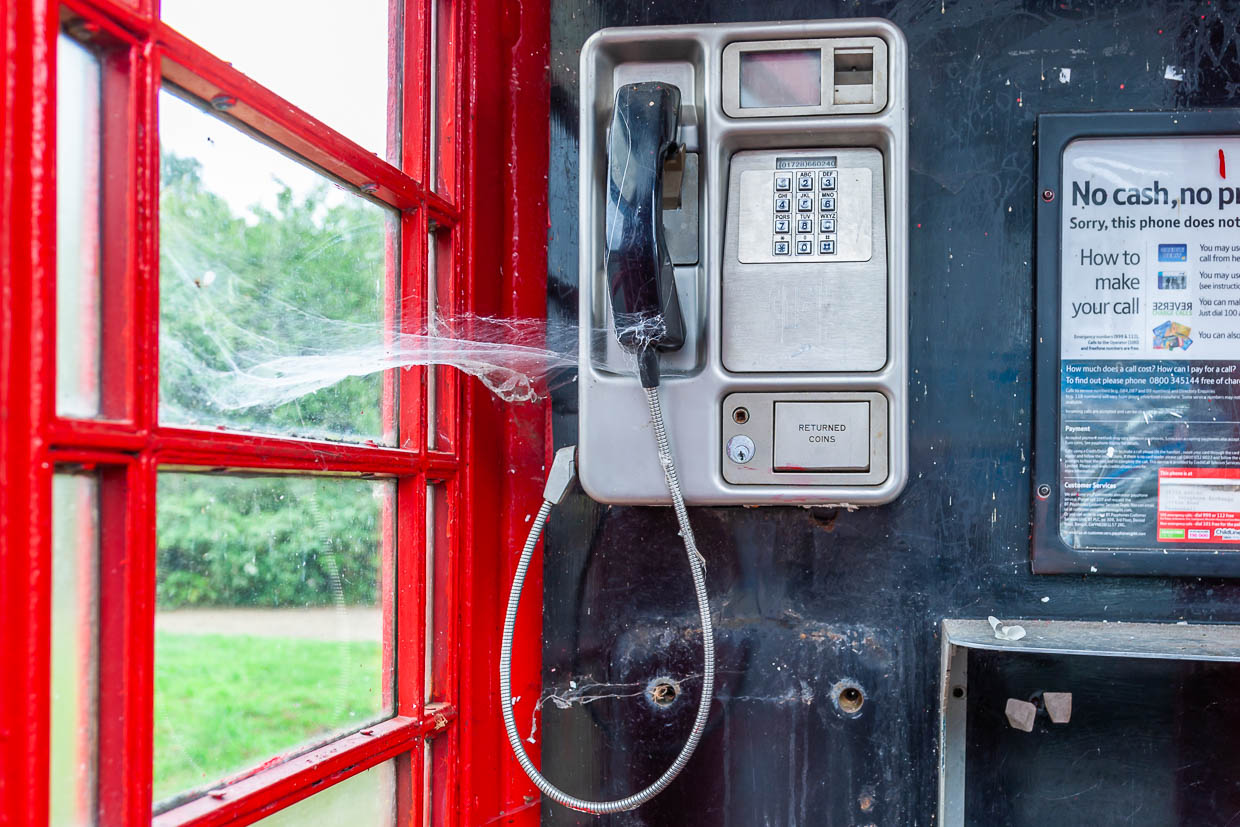 Una cabina telefónica roja tradicional en un entorno rural del Reino Unido muestra una tela de araña sobre el receptor / © Foto: Georg Berg