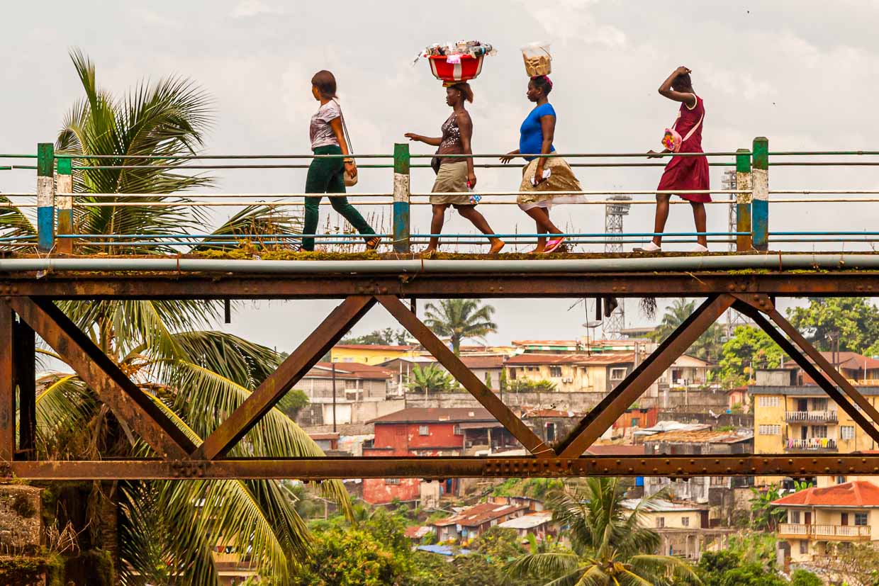 Mujeres cruzan el antiguo puente ferroviario de Freetown, el puente Tengbeh, cargando mercancías sobre sus cabezas / © Foto: Georg Berg