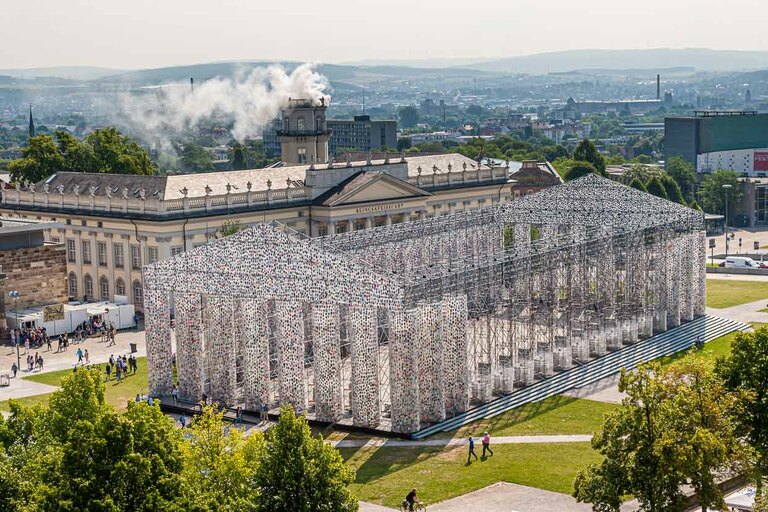 Partenón de los libros, de la artista argentina Marta Minujin en la documenta 14 de Kassel. Cada día, la construcción, que es una réplica del templo de la Acrópolis en cuanto a sus dimensiones, se hacía más maciza y se llenaba de más libros. Al fondo, la instalación "Expiration Movement" humea en la Zwehrenturm / © Foto: Georg Berg