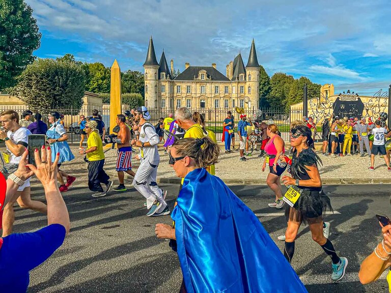 El colorido pelotón frente a un telón de fondo histórico. En el recorrido del maratón, los participantes del 36º Maratón des Chateaux du Medoc pasan por un total de 25 bodegas. A menudo pasan por el centro del recinto del castillo y se les ofrece vino tinto y agua / © Foto: Georg Berg