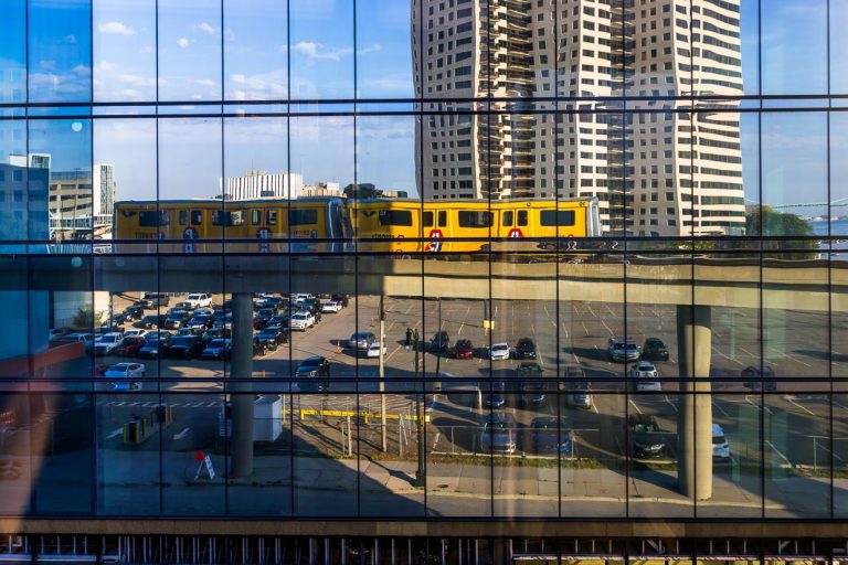 Reflejo del Detroit People Mover. Se trata de un sistema ferroviario elevado de 4,7 kilómetros de longitud y funcionamiento automático que atraviesa el centro de Detroit. Los pasajeros de la línea de circunvalación son turistas y empleados de las tiendas y oficinas del centro de la ciudad. El viaje cuesta 25 céntimos y ofrece una interesante vista de los edificios del centro de Detroit / © Foto: Georg Berg