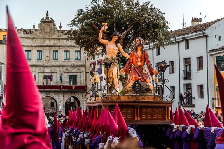 Procesión en España con Jesús y un ángel en una carroza; los peregrinos visten túnicas rojas y moradas / © Foto: Georg Berg