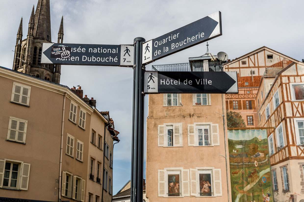 Señales en el centro de Limoges que indican los lugares de interés de la ciudad, como el Museo Nacional Adrien Dubouché, la carnicería y el ayuntamiento; al fondo, un mural al estilo de las antiguas casas con entramado de madera / © Fotografía: Georg Berg