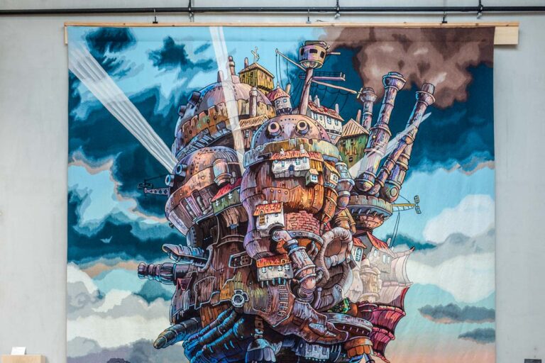 Gewebte Abenteuer in den Ausstellungsräumen der Cité internationale de la tapisserie Aubusson. Hier „The moving castle at sunset“ aus dem Animefilm von 2004 Howl’s Moving Castle. Gewebt in Aubusson ab März 2022 bis Februar 2023 / © Foto: Georg Berg