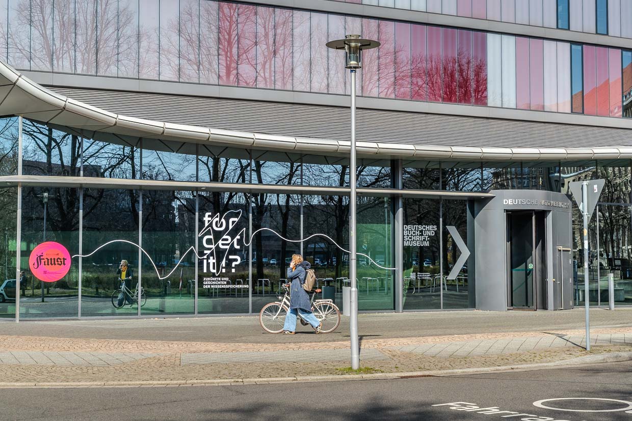 Frau fährt Fahrrad vor dem Deutschen Buch- und Schriftmuseum in Leipzig, Germany
